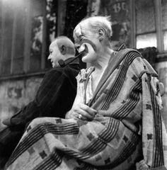 an old photo of two men with clown noses on their faces, one sitting down and the other standing up