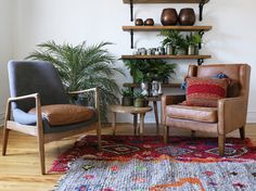 two chairs and a table in a room with potted plants on the shelf above them