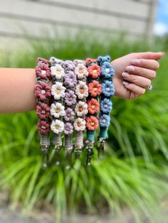 a woman's arm with bracelets made out of crocheted beads and flowers