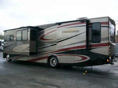 a motor home parked in a parking lot next to a truck and trailer with the word crescendo written on it