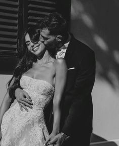 black and white photograph of a bride and groom embracing each other in front of shutters