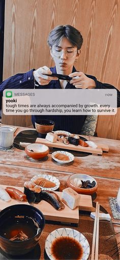 a man sitting at a table with sushi and chopsticks in front of him