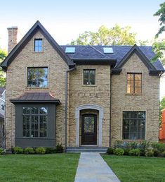 a large brick house with green grass and trees