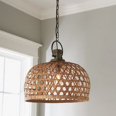 a wooden light fixture hanging from a ceiling in a room with white walls and windows