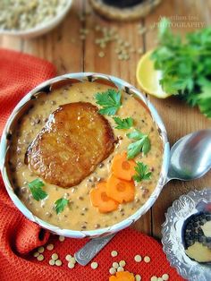 a bowl filled with soup and carrots on top of a wooden table next to other foods