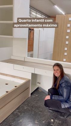 a woman sitting on the ground in front of a desk with drawers and shelves behind her