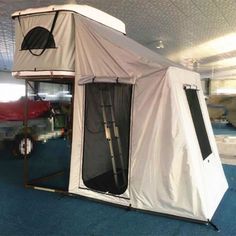 a tent that is sitting in the middle of a room with blue carpet and white walls