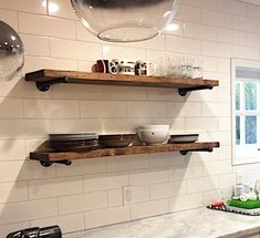 two wooden shelves in a kitchen with plates and bowls on them