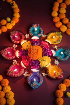 an arrangement of colorful candles and flowers on a purple surface