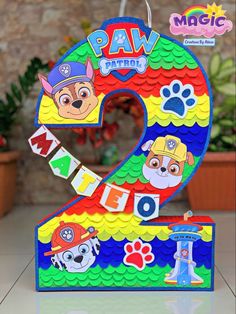 the number two is made out of paper and has paw patrol characters on it's sides