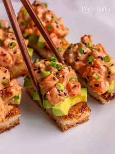 several pieces of sushi with chopsticks sticking out of them on a white plate