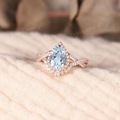 a blue topazte and diamond ring sitting on a white blanket in front of a pillow