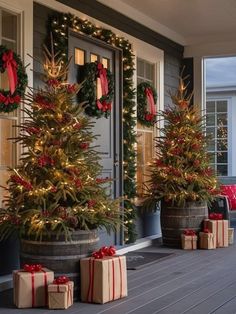 three christmas trees are on the porch with presents under them and wrapped in red ribbon