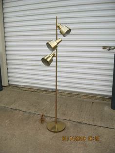 a three light floor lamp in front of a garage door