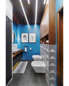 a bathroom with blue walls and wood ceilinging, two sinks and three urinals