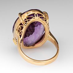 This superb vintage cocktail ring is accented with one (1) oval cut natural amethyst that weighs approximately 22.60cts that is set into a four-prong setting. The gallery features an openwork design. The ring measures 23.9mm at the top, rises 10.5mm above the finger, tapering to 2.6mm wide and 1.5mm thick at the base of the shank. It is currently a size 6.25. Luxury Purple Amethyst Oval Cabochon Ring, Formal Polished Amethyst Oval Cabochon Ring, Formal Oval Cabochon Amethyst Ring With Polished Finish, Art Deco Purple Amethyst Ring For Formal Occasions, Purple Amethyst Art Deco Ring For Formal Occasions, Formal Art Deco Purple Amethyst Ring, Luxury Polished Oval Amethyst Ring, Luxury Oval Amethyst Ring With Polished Finish, Formal Oval Cabochon Amethyst Ring