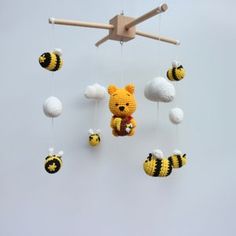 a crocheted teddy bear and bees hanging from a wooden mobile with white balls