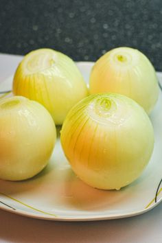 three onions are sitting on a white plate