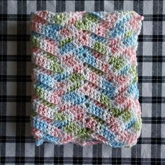 a crocheted dishcloth is sitting on a checkered table cloth