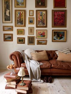 a living room filled with furniture and lots of framed pictures on the wall above it