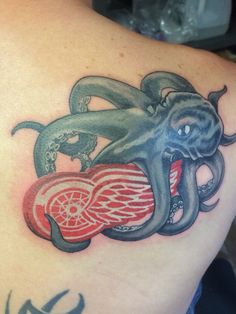 an octopus tattoo on the back of a man's shoulder with wings and heart