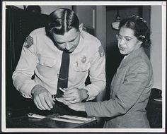 an old black and white photo of two people in uniform looking at something on a table