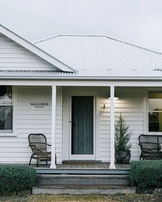 a white house with two chairs on the front porch