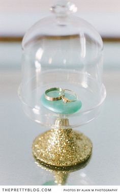 a ring is sitting on top of a glass dome with gold flecks around it