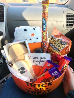 a person holding a bowl filled with candy and snacks