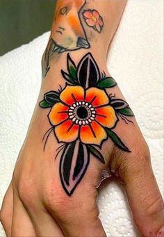 a woman's hand with an orange flower on it