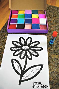 a box filled with crayons next to a flower cut out on paper and markers