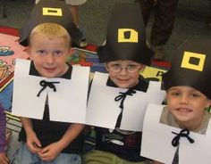 three children with paper hats on their heads sitting in the middle of a carpeted area