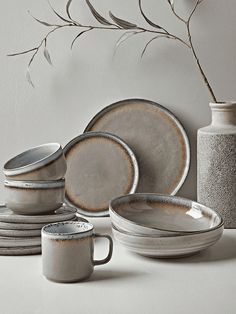 a table topped with plates and cups next to a vase