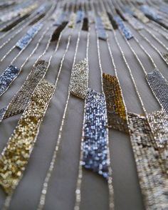 many different types of sequins and beads on a table cloth with silver, gold, and blue colors