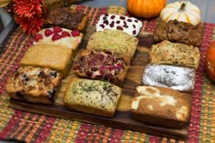 a wooden cutting board topped with lots of different types of cakes