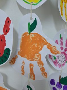 paper handprints hanging from clothes pins on a white background with flowers and leaves