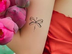 a woman's arm with a tattoo on it and pink flowers in the background