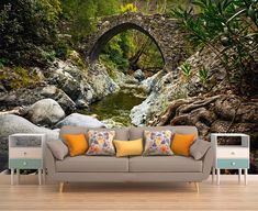 a couch sitting in front of a wall with a stone bridge over a river on it