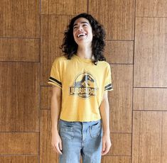 a young woman standing in front of a wooden wall and smiling at the camera with her mouth wide open