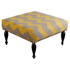 a yellow and gray ottoman sitting on top of a black wooden legs with an upholstered foot rest