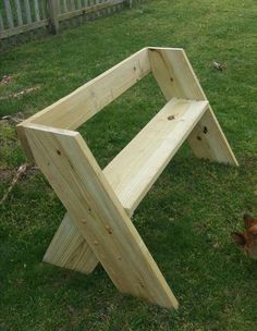 a wooden bench sitting in the grass next to a small chicken laying on the ground