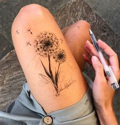 a woman with a dandelion tattoo on her thigh