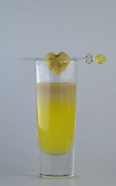 a glass filled with yellow liquid on top of a table