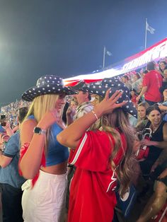 two women in red and white outfits at a sporting event with an american flag on the sidelines