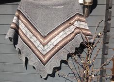 a knitted shawl hanging on the side of a house next to a potted plant