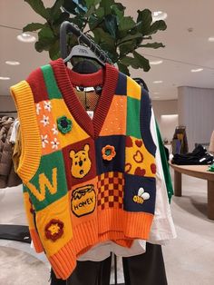 a colorful sweater hanging on a rack in a clothing store next to a potted plant