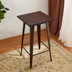 a small wooden table sitting on top of a rug next to a potted plant