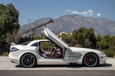 a white sports car with its doors open and mountains in the back ground behind it