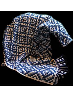 a blue and white crocheted hat with tassels on the side, sitting on a black background