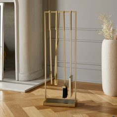 a vase with some plants in it on a wooden floor next to a gold sculpture